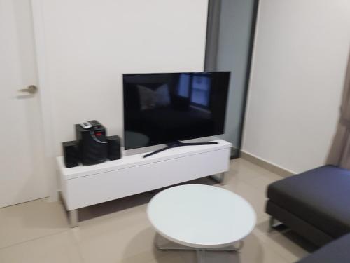 ein Wohnzimmer mit einem TV und einem weißen Stuhl in der Unterkunft Relaxing Studio@Cyber in Cyberjaya