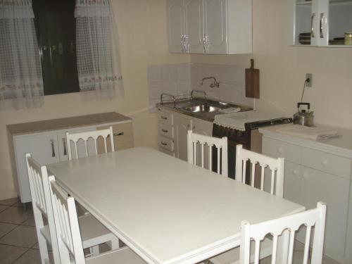 a kitchen with a white table and chairs in it at Casa para aluguel de verão in Torres