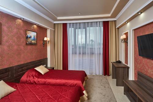 Habitación de hotel con cama roja y TV en Gostinitsa Krasnaya en Blagovéshchensk