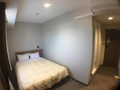 um pequeno quarto com uma cama num quarto em Hotel Crown Hills Onahama em Iwaki