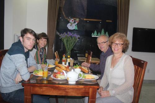 een groep mensen die aan een tafel zitten en eten bij An Bang Beach Dolphin Homestay in Hội An