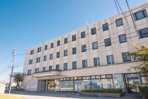 a large tan building with windows on a street at Sky Hotel Namerikawa in Namerikawa