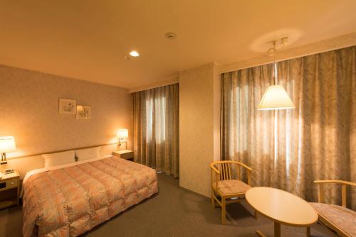 a hotel room with a bed and a table and chair at Sky Hotel Namerikawa in Namerikawa