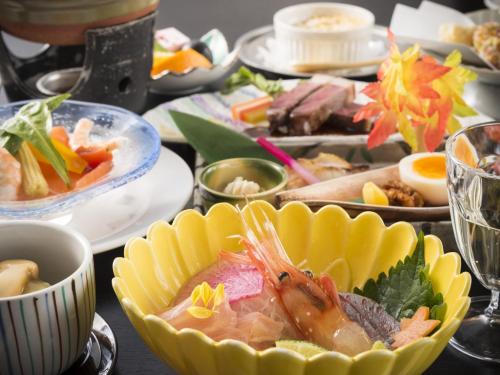 a table topped with plates and bowls of food at Sky Hotel Namerikawa in Namerikawa