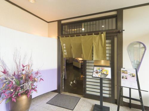 a front door of a store with a window and flowers at Sky Hotel Namerikawa in Namerikawa