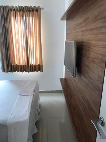 a bathroom with a tv on the wall and a curtain at V G Fun Praia Do Futuro in Fortaleza