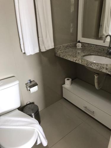 a bathroom with a sink and a toilet and a mirror at V G Fun Praia Do Futuro in Fortaleza