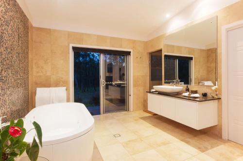 y baño con bañera blanca y lavamanos. en Deja Vu Estate, en Pokolbin