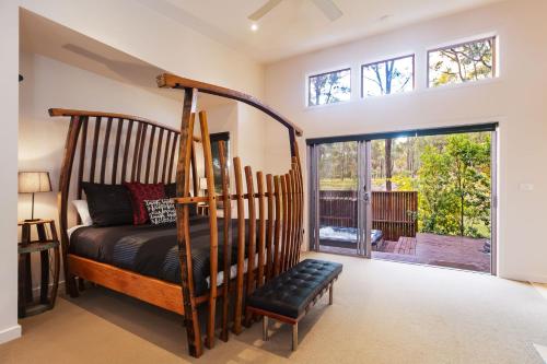 a bedroom with a wooden bed and a large window at Deja Vu Estate in Pokolbin