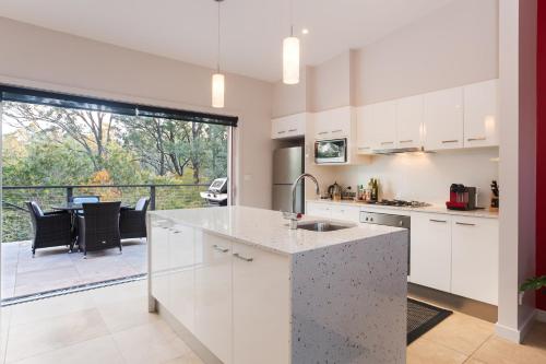 a kitchen with white cabinets and a view of a patio at Deja Vu Estate in Pokolbin