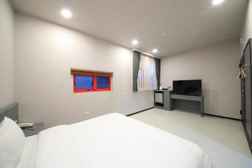 a white bedroom with a bed and a television at 花蓮亮君經典民宿1館加2館民宿-東大門夜市-電梯包棟Bright King Homestay in Hualien City