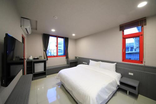 a bedroom with a large white bed and two windows at 花蓮亮君經典民宿1館加2館民宿-東大門夜市-電梯包棟Bright King Homestay in Hualien City