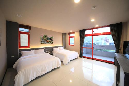 a bedroom with two beds and a large window at 花蓮亮君經典民宿1館加2館民宿-東大門夜市-電梯包棟Bright King Homestay in Hualien City