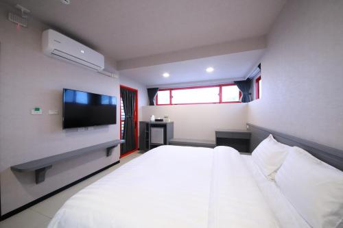 a bedroom with a white bed and a flat screen tv at 花蓮亮君經典民宿1館加2館民宿-東大門夜市-電梯包棟Bright King Homestay in Hualien City