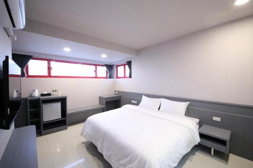 a bedroom with a white bed and a desk at 花蓮亮君經典民宿1館加2館民宿-東大門夜市-電梯包棟Bright King Homestay in Hualien City