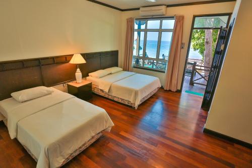 a bedroom with two beds and a view of the ocean at Tuna Bay Island Resort in Perhentian Islands