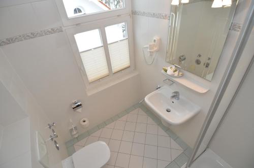 y baño blanco con lavabo y ducha. en Villa Malepartus - Wohnung 07, en Binz