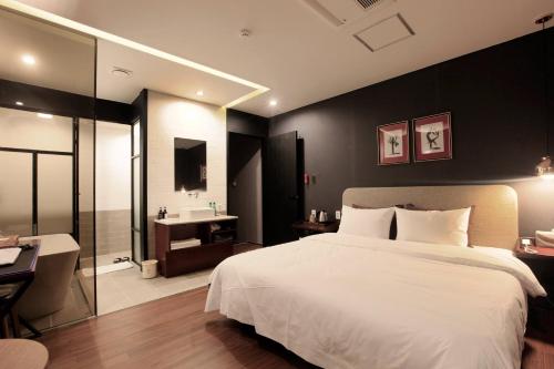 a bedroom with a large white bed and a bathroom at Seomyeon Brown-dot hotel Gold in Busan