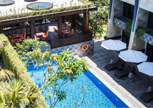 an outdoor patio with umbrellas and a swimming pool at Solia Legian Bali in Legian