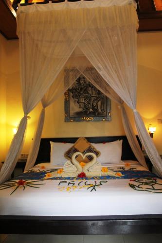 a bedroom with a canopy bed with an owl on it at Mans Cottages & Spa in Pemuteran