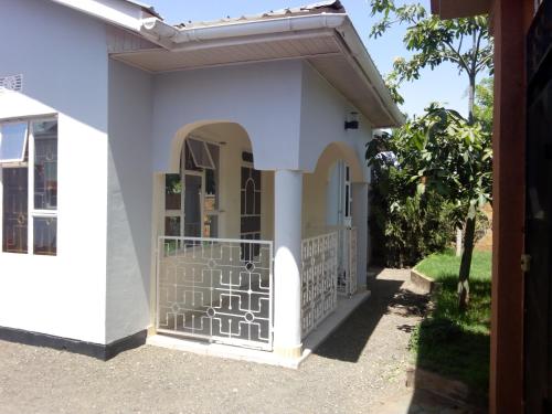 a white house with a gate and an archway at Le Parlour in Boma la Ngombe