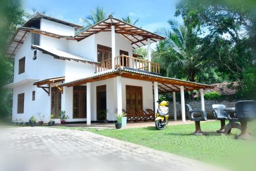 a white house with a scooter in front of it at Hotel Nimjaya in Udawalawe