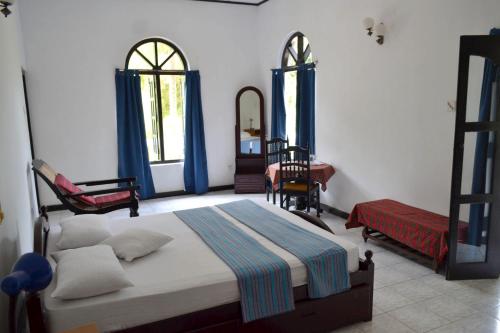 1 dormitorio con cama, silla y espejo en Hotel Breeta's Garden, en Ginigathena
