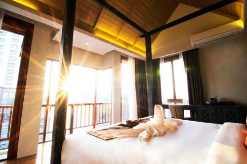 a bedroom with a bed and a balcony with windows at Tapae Gate Villa in Chiang Mai