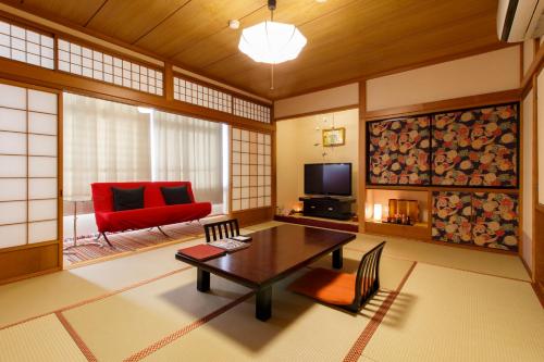 a living room with a table and a red chair at Oyado Koto No Yume in Takayama
