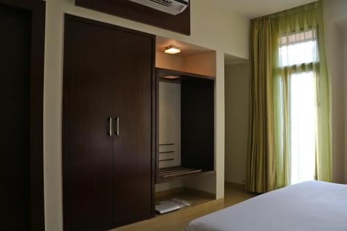 a bedroom with a large black cabinet with a mirror at The Waterfront Shaw Lavasa in Lavasa