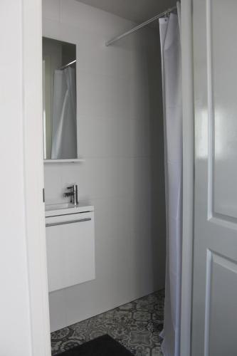 Un baño blanco con lavabo y espejo. en Viale, en Egmond aan Zee