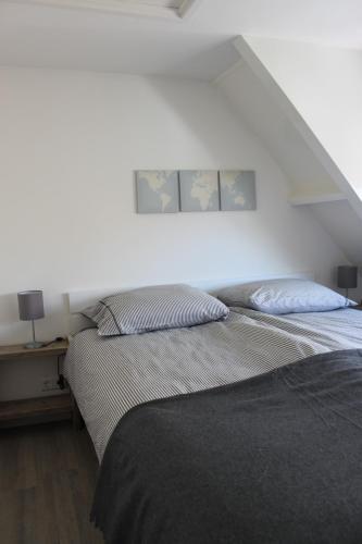 Un dormitorio con dos camas y una pared blanca. en Viale, en Egmond aan Zee