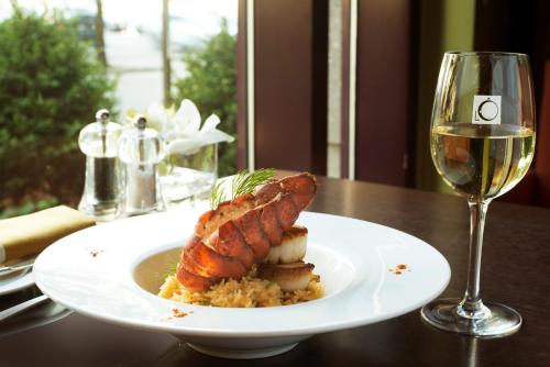 a white plate with a piece of meat and a glass of wine at Novotel Montreal Center in Montréal