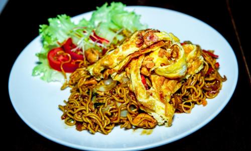 a plate of food with noodles and a salad at Kubu Garden Suites & Villas Nusa Dua in Nusa Dua