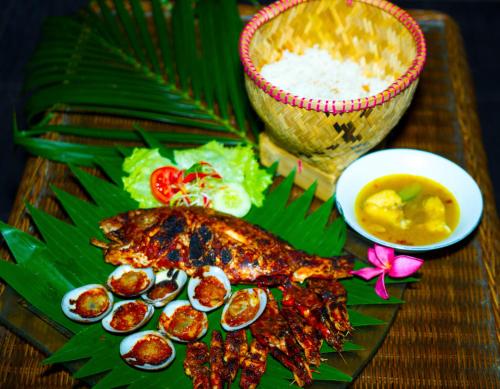 a plate of food with fish and a bowl of sauce at Kubu Garden Suites & Villas Nusa Dua in Nusa Dua