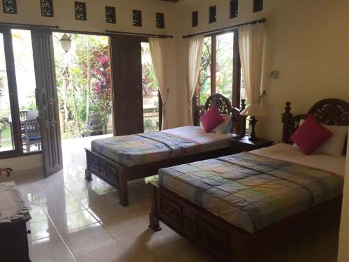 two beds sitting in a room with windows at Bagus Homestay in Ubud