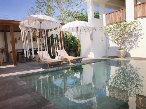 a swimming pool with two chairs and umbrellas next to a house at Villa S in Hua Hin