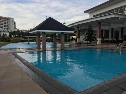 - une grande piscine avec un kiosque à côté d'un bâtiment dans l'établissement JJ Suites Tagaytay @ Wind Residences, à Tagaytay