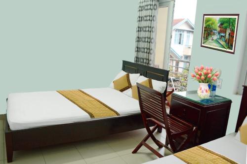 a bedroom with a bed and a table and a chair at Cat An Guesthouse in Hue