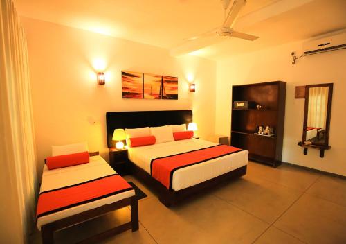 a hotel room with two beds and a chair at Celestial Inn in Mirissa