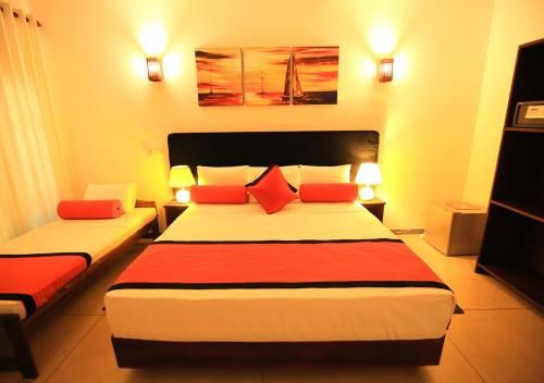 a hotel room with two beds with red pillows at Celestial Inn in Mirissa