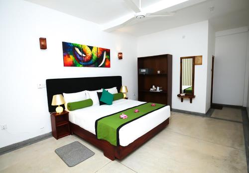 a bedroom with a large bed with a green blanket at Celestial Inn in Mirissa