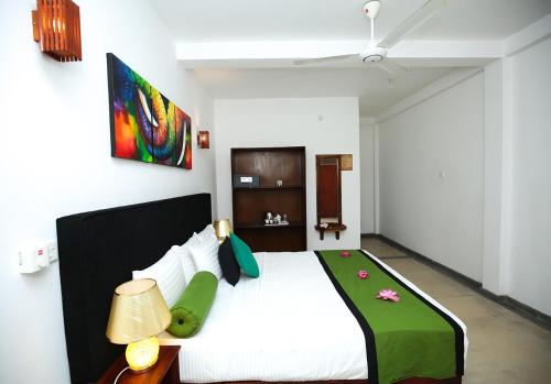 a bedroom with a large bed with a green blanket at Celestial Inn in Mirissa