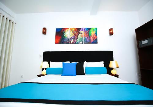 a bedroom with a blue and white bed with two lamps at Celestial Inn in Mirissa