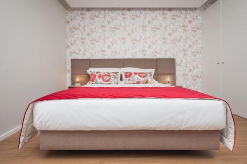 a bedroom with a large bed with red blankets and pillows at Essence Inn Marianos Hotel in Fátima
