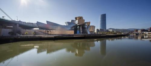 a large building next to a river with a bridge at Hotel Ilunion Bilbao in Bilbao