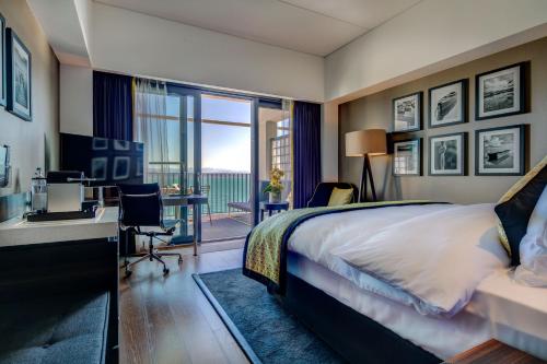 a hotel room with a bed and a desk and a balcony at Hotel Beaulac in Neuchâtel
