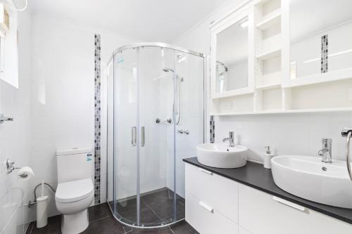 a bathroom with a shower and two sinks and a toilet at Views Forever - Devonport in Devonport