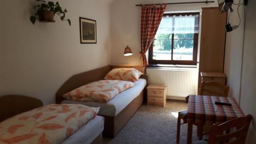 a bedroom with two beds and a table and a window at Chata u Tří Sluk in Modrava