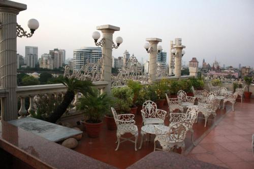 a row of white chairs and tables on a balcony at Garden Hotel in Mumbai